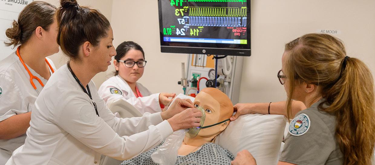 Students putting oxygen mask on simulated patient